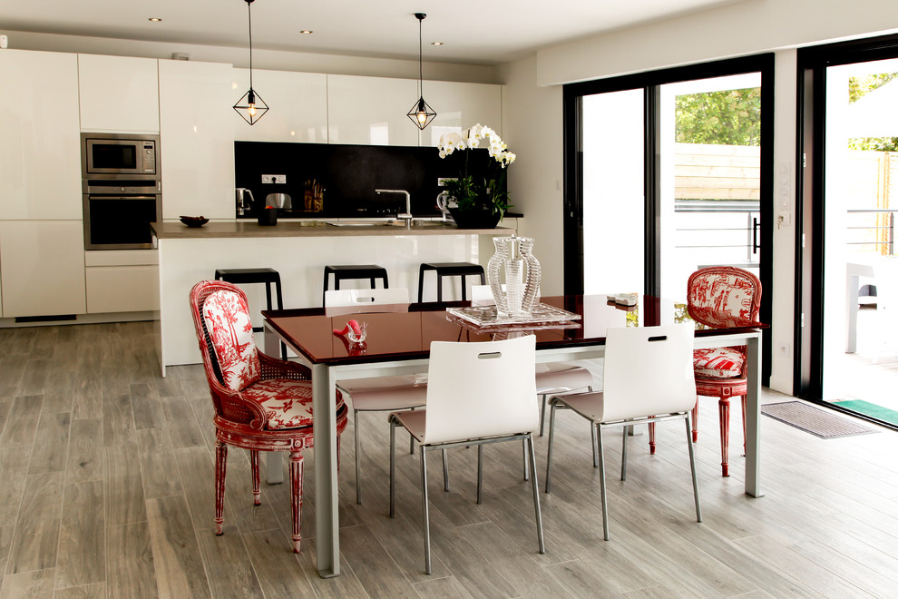 Inspiration for a mid-sized contemporary kitchen/dining combo in Rennes with white walls and light hardwood floors.