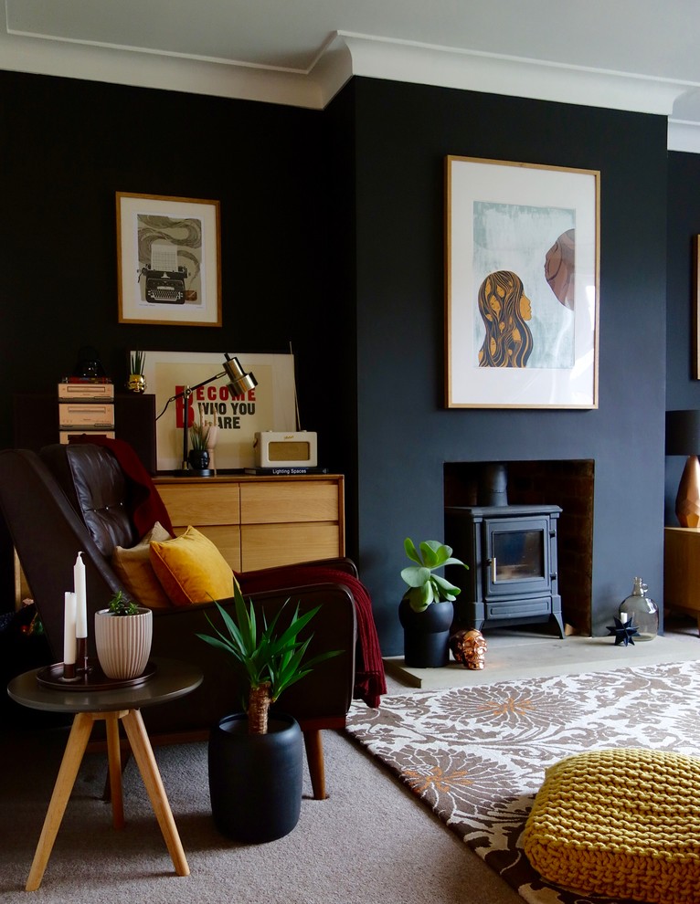 Photo of a mid-sized midcentury enclosed living room in Other with black walls, carpet, a wood stove and a plaster fireplace surround.