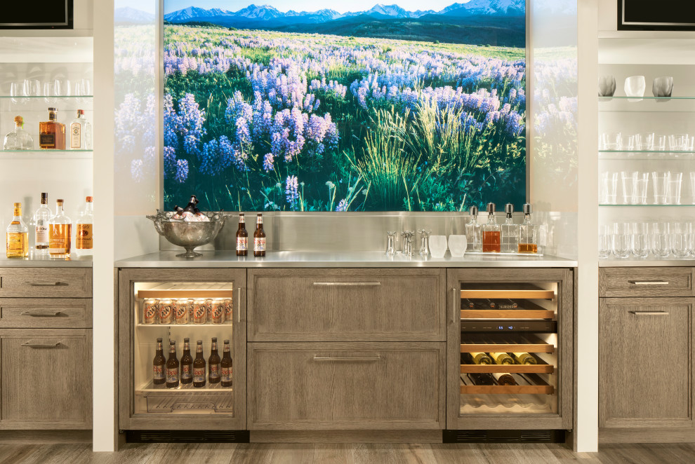 Photo of a mid-sized country u-shaped home bar in Denver with an undermount sink, recessed-panel cabinets, grey cabinets, wood benchtops, white splashback, medium hardwood floors, grey floor and white benchtop.