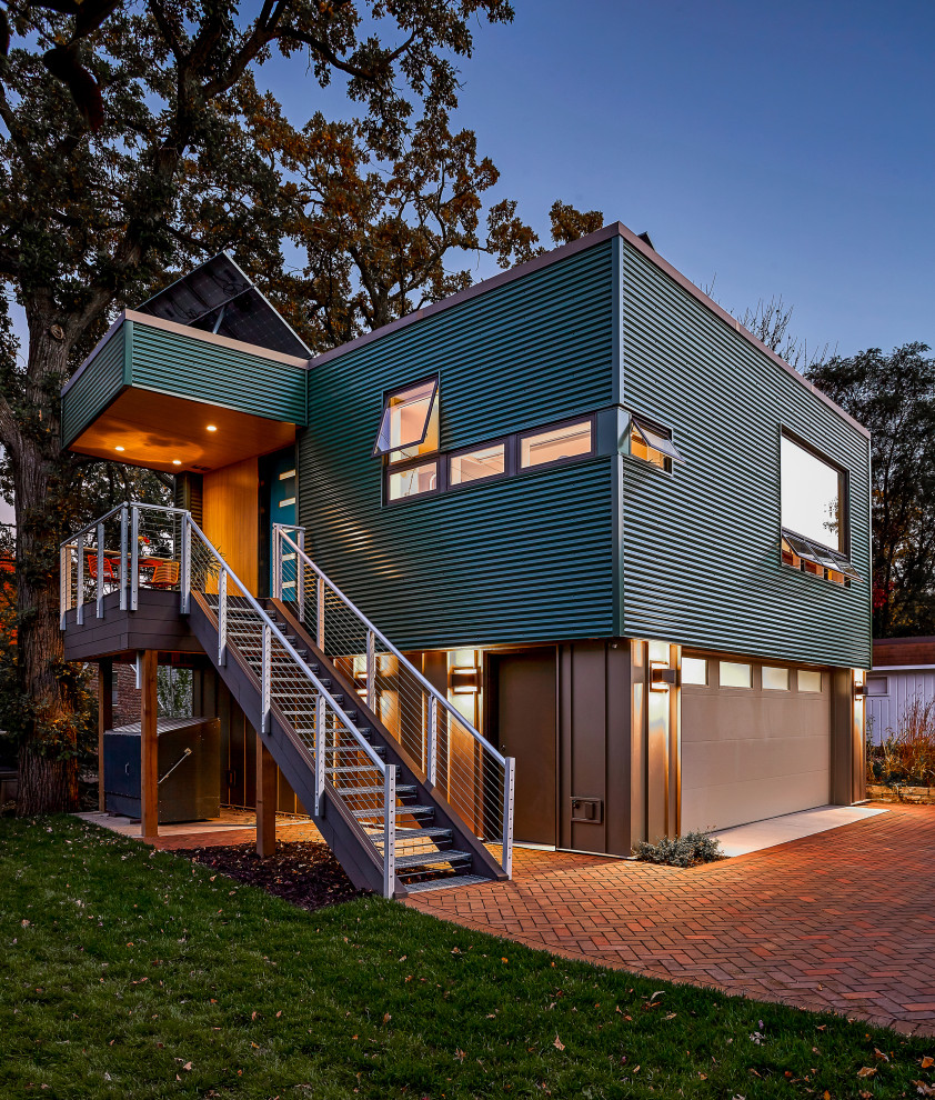 Foto på ett litet funkis grönt hus, med två våningar, metallfasad och platt tak