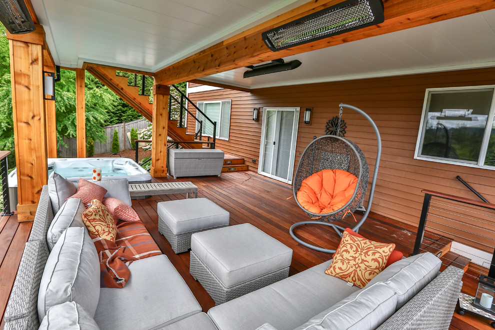 Example of a large minimalist backyard deck design in Seattle with a roof extension