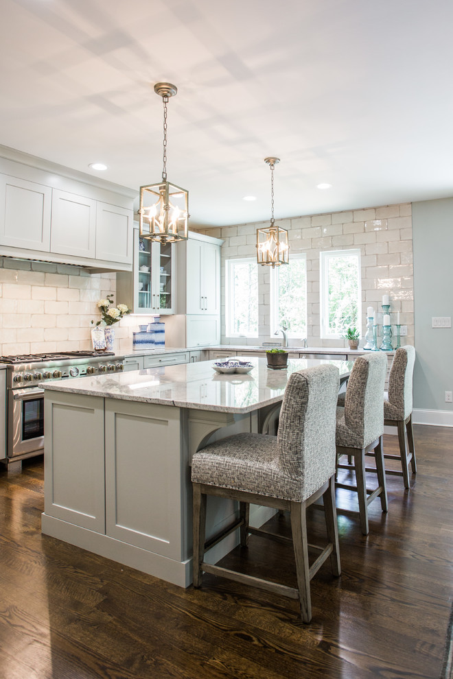 This is an example of a transitional u-shaped eat-in kitchen in Charlotte with shaker cabinets, grey cabinets, white splashback, subway tile splashback, stainless steel appliances, medium hardwood floors, with island, brown floor, white benchtop and an undermount sink.