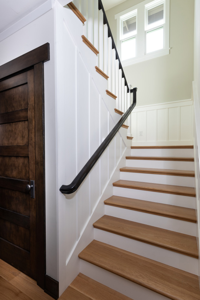 Foto de escalera de estilo americano grande con escalones de madera, contrahuellas de madera, barandilla de madera y boiserie
