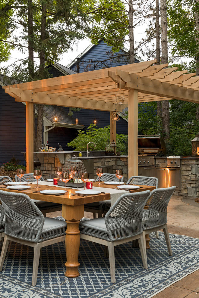 Inspiration for a mid-sized traditional backyard patio in Minneapolis with an outdoor kitchen, natural stone pavers and a pergola.