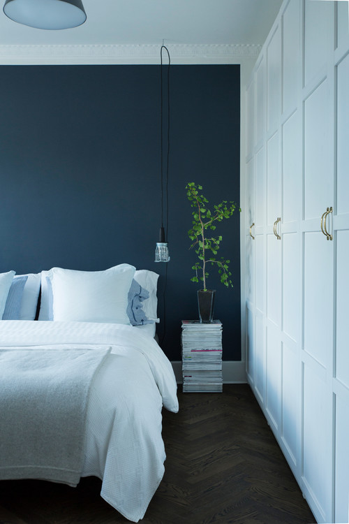 blue minimalist bedroom, navy blue accent wall and white bedding 