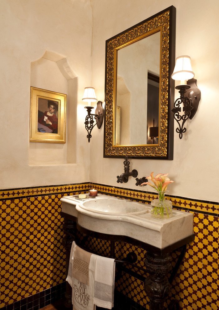 Photo of a mid-sized mediterranean powder room in Santa Barbara with furniture-like cabinets, brown tile, yellow tile, ceramic tile, white walls and marble benchtops.