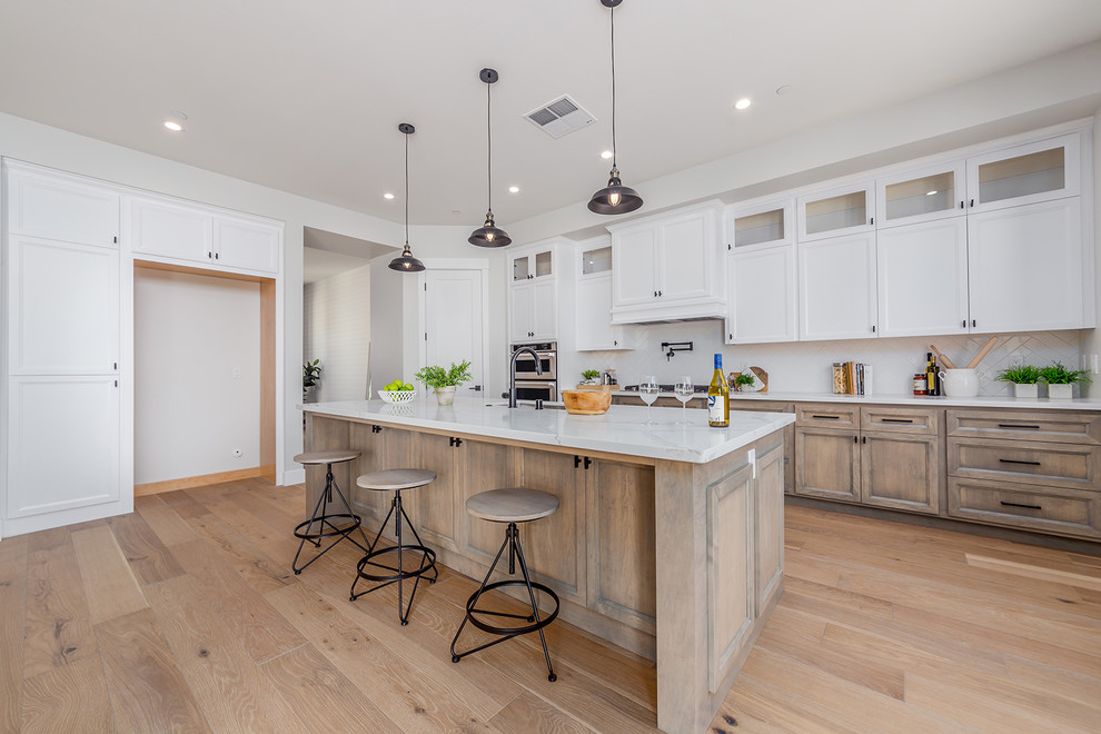 This is an example of a mid-sized country l-shaped kitchen pantry in Sacramento with an integrated sink, flat-panel cabinets, medium wood cabinets, ceramic splashback, stainless steel appliances, light hardwood floors, with island and beige floor.