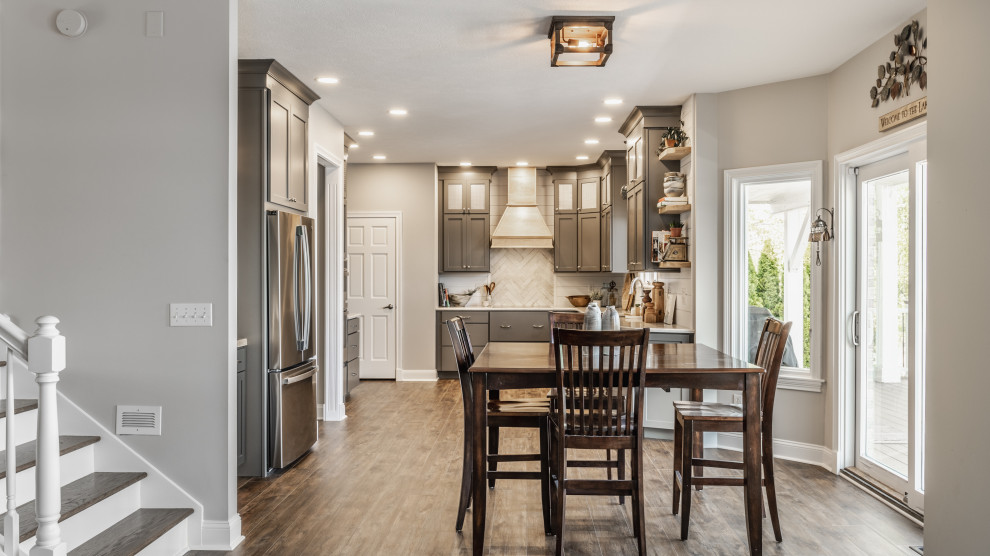 Design ideas for a large transitional l-shaped eat-in kitchen in Indianapolis with an undermount sink, shaker cabinets, grey cabinets, quartz benchtops, white splashback, shiplap splashback, stainless steel appliances, vinyl floors, no island and brown floor.