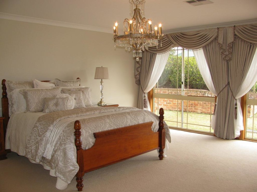This is an example of a traditional master bedroom in Sydney with beige walls and carpet.