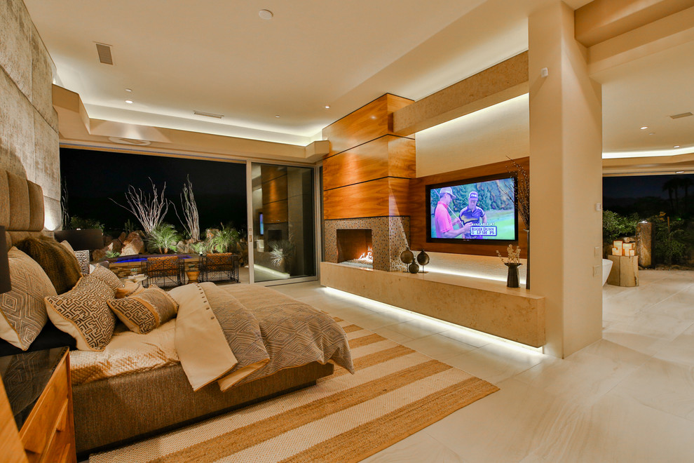 Large contemporary master bedroom in Los Angeles with beige walls, porcelain floors, a standard fireplace, a tile fireplace surround and beige floor.