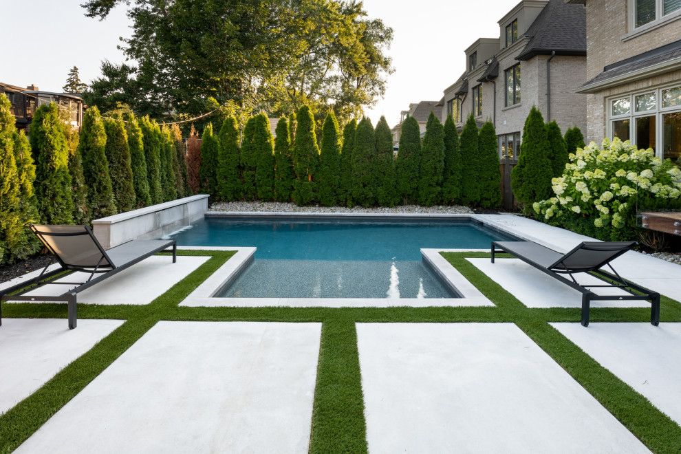This is an example of a small traditional back rectangular swimming pool in Toronto with with pool landscaping and stamped concrete.