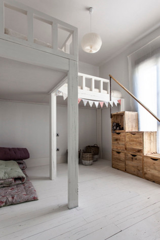 Design ideas for a large country gender-neutral kids' bedroom for kids 4-10 years old in Madrid with white walls and painted wood floors.