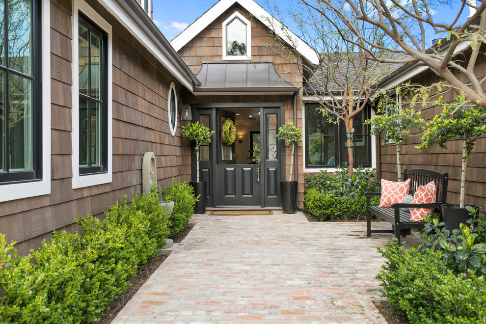 Inspiration for a transitional front door in Orange County with brown walls, brick floors, a dutch front door and a black front door.