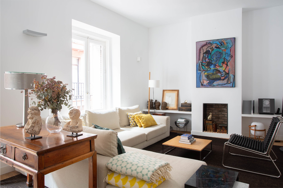This is an example of a mid-sized contemporary open concept living room in Madrid with white walls, a standard fireplace, a library and no tv.