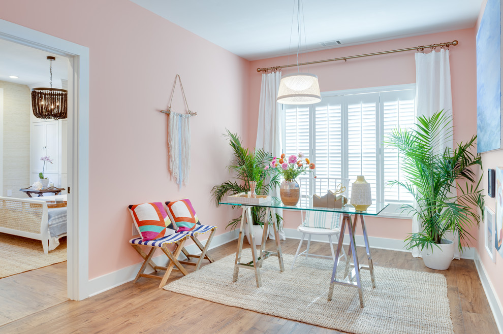Photo of a mid-sized tropical study room in Atlanta with pink walls, medium hardwood floors, a freestanding desk, no fireplace and brown floor.