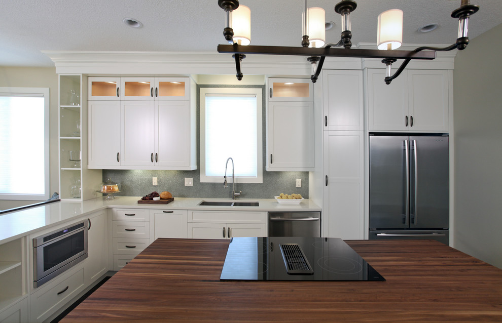Example of a large transitional l-shaped dark wood floor eat-in kitchen design in Calgary with an undermount sink, shaker cabinets, white cabinets, quartz countertops, gray backsplash, stainless steel appliances and an island