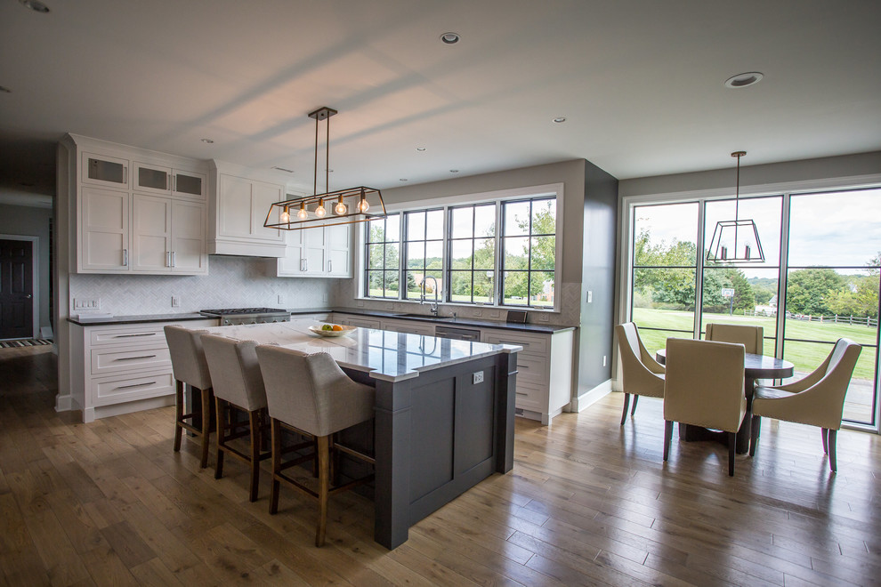 Mid-sized transitional l-shaped medium tone wood floor and brown floor eat-in kitchen photo in Baltimore with an undermount sink, shaker cabinets, white cabinets, marble countertops, white backsplash, marble backsplash, stainless steel appliances, an island and white countertops