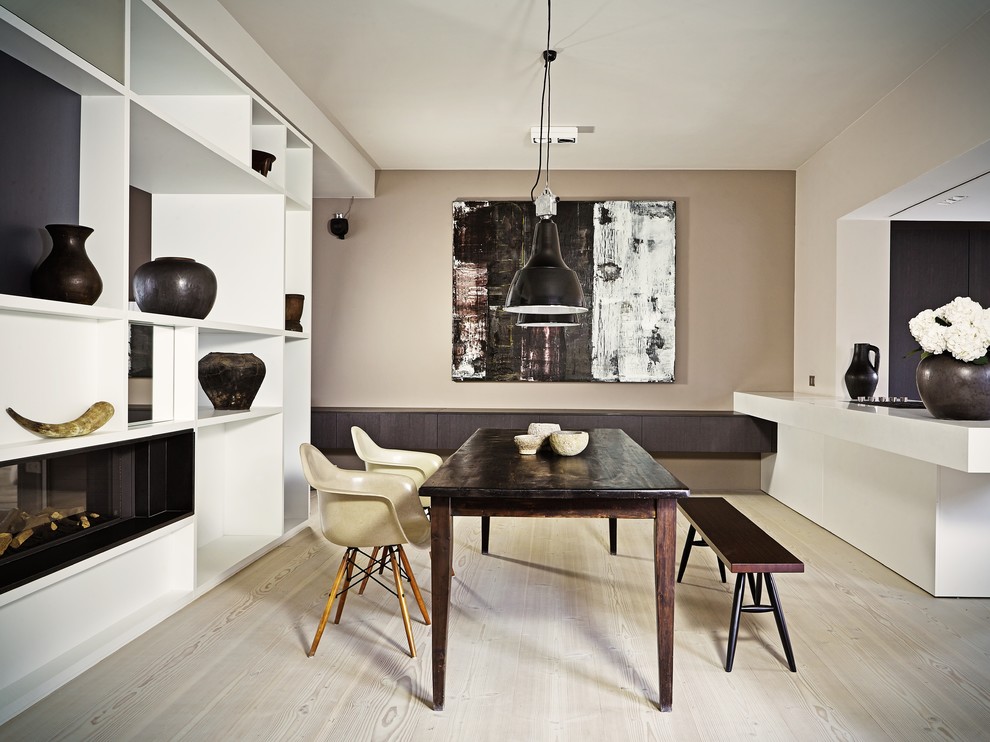 This is an example of a mid-sized contemporary dining room in Berlin with beige walls, light hardwood floors, a two-sided fireplace and a plaster fireplace surround.