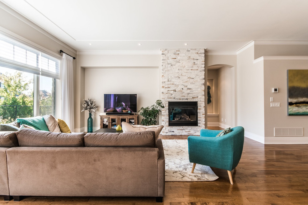 Photo of a mid-sized contemporary open concept living room in Montreal with beige walls, medium hardwood floors, a standard fireplace, a stone fireplace surround, a freestanding tv and brown floor.