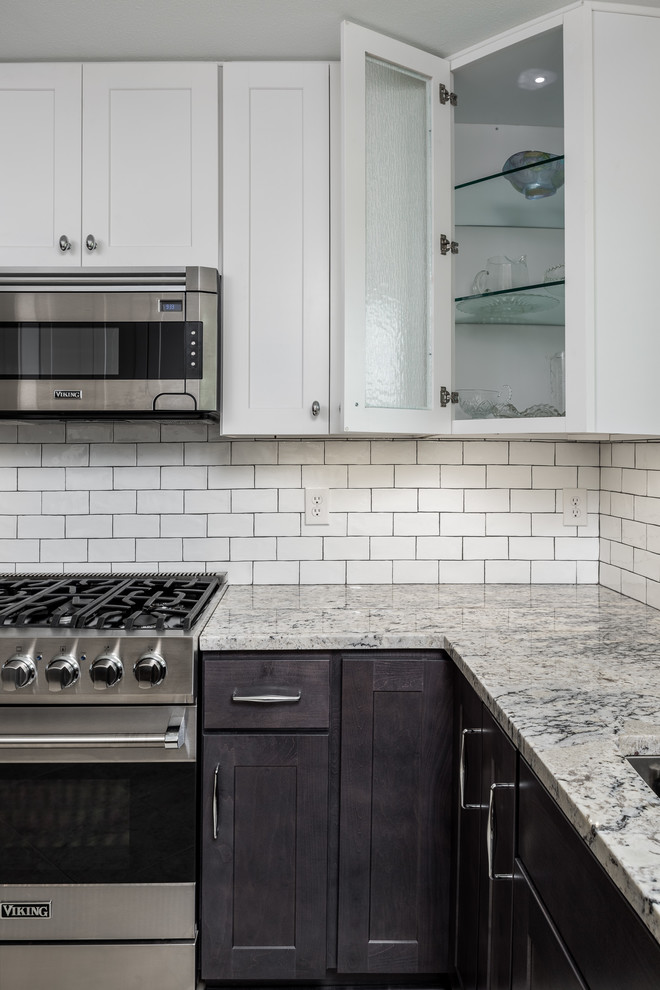Inspiration for a mid-sized transitional u-shaped eat-in kitchen in Dallas with an undermount sink, glass-front cabinets, black cabinets, marble benchtops, white splashback, subway tile splashback, stainless steel appliances, porcelain floors, with island and white floor.