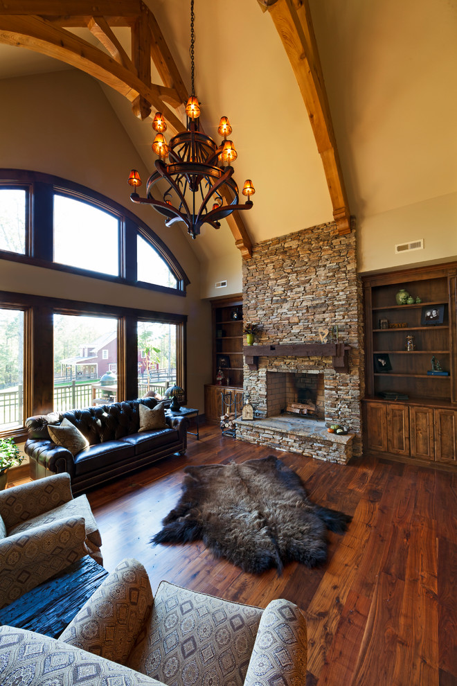Photo of a large country formal open concept living room in Charlotte with beige walls, dark hardwood floors, a standard fireplace, a stone fireplace surround, no tv and brown floor.
