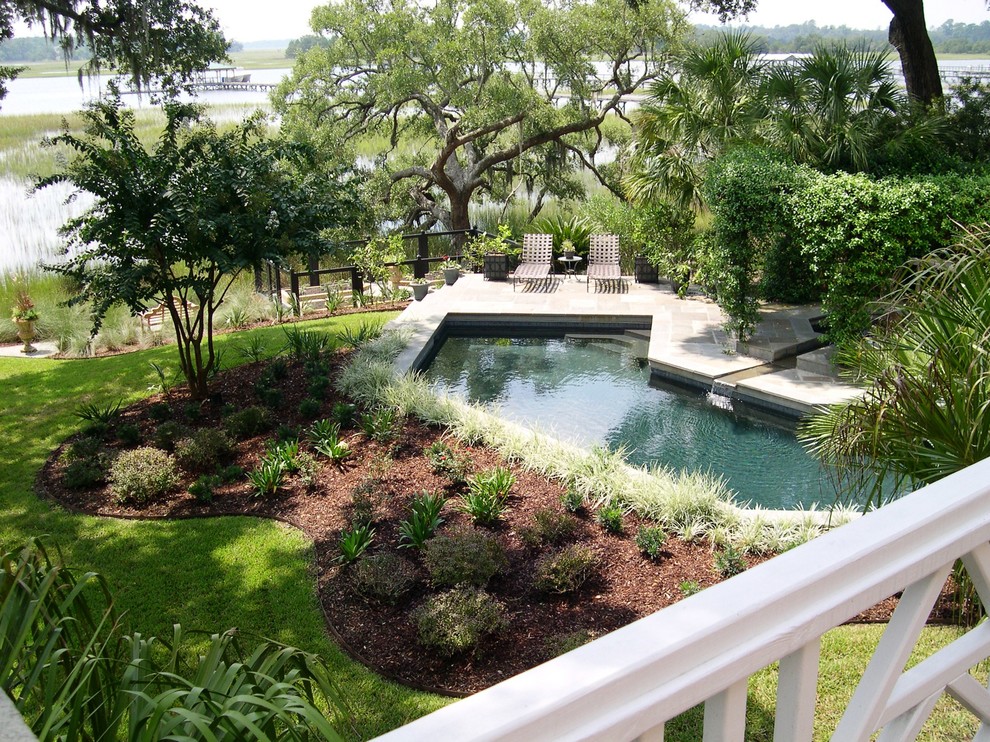 This is an example of a large contemporary backyard garden for summer in Charleston with a water feature and natural stone pavers.