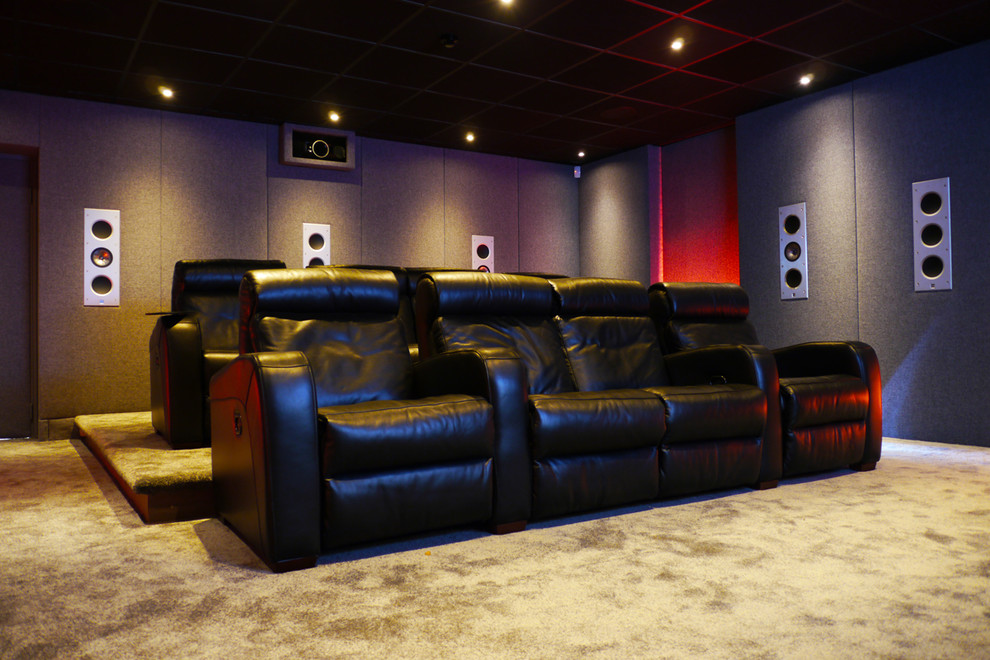 This is an example of a large modern home theatre in Sussex with grey walls, carpet and a projector screen.
