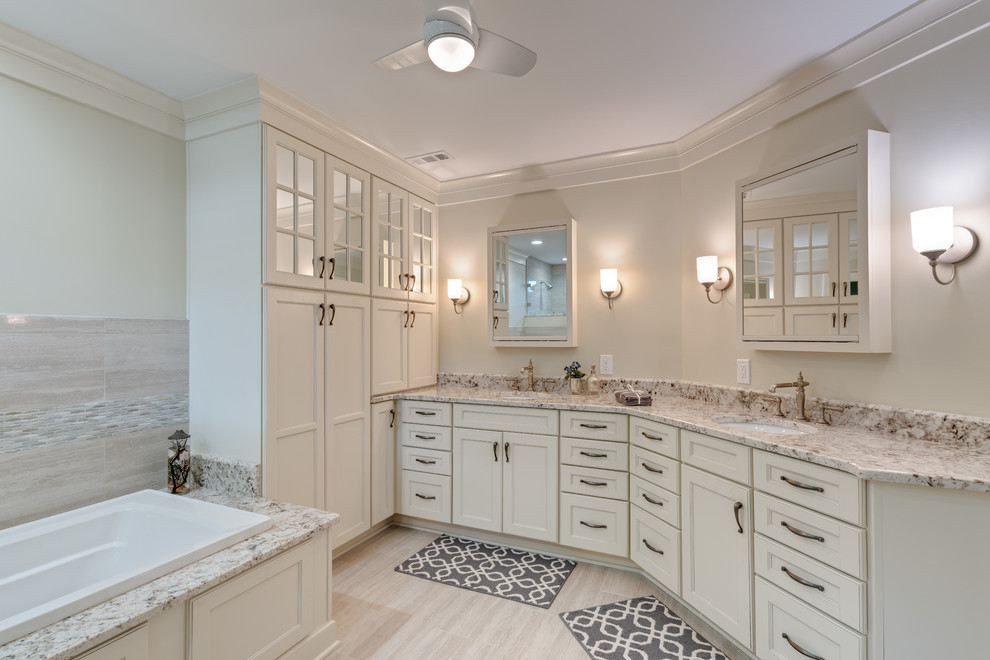 This is an example of a large transitional master bathroom in Atlanta with recessed-panel cabinets, white cabinets, a drop-in tub, white walls, porcelain floors, an undermount sink, granite benchtops, beige floor, white benchtops, an enclosed toilet, a double vanity, a built-in vanity, an open shower and an open shower.