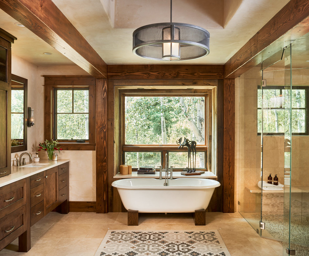Design ideas for a country master bathroom in Denver with shaker cabinets, dark wood cabinets, a freestanding tub, a curbless shower, beige tile, an undermount sink, granite benchtops and travertine.