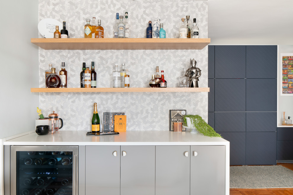 Design ideas for a mid-sized contemporary single-wall home bar in New York with flat-panel cabinets, grey cabinets, quartz benchtops, grey splashback, no sink, medium hardwood floors and brown floor.