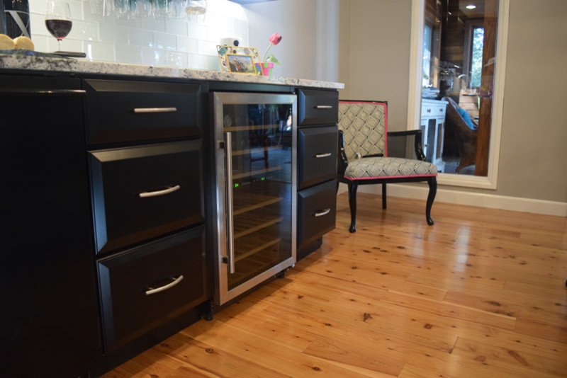 Kitchen - transitional medium tone wood floor kitchen idea in Chicago with a farmhouse sink, raised-panel cabinets, black cabinets, quartz countertops, white backsplash, glass tile backsplash, stainless steel appliances and an island