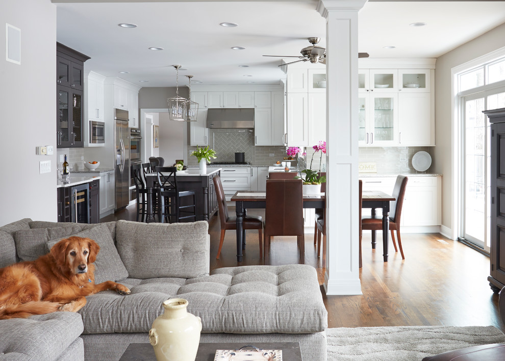 Inspiration for a large transitional u-shaped medium tone wood floor open concept kitchen remodel in Chicago with a double-bowl sink, flat-panel cabinets, white cabinets, quartz countertops, beige backsplash, subway tile backsplash, stainless steel appliances and an island