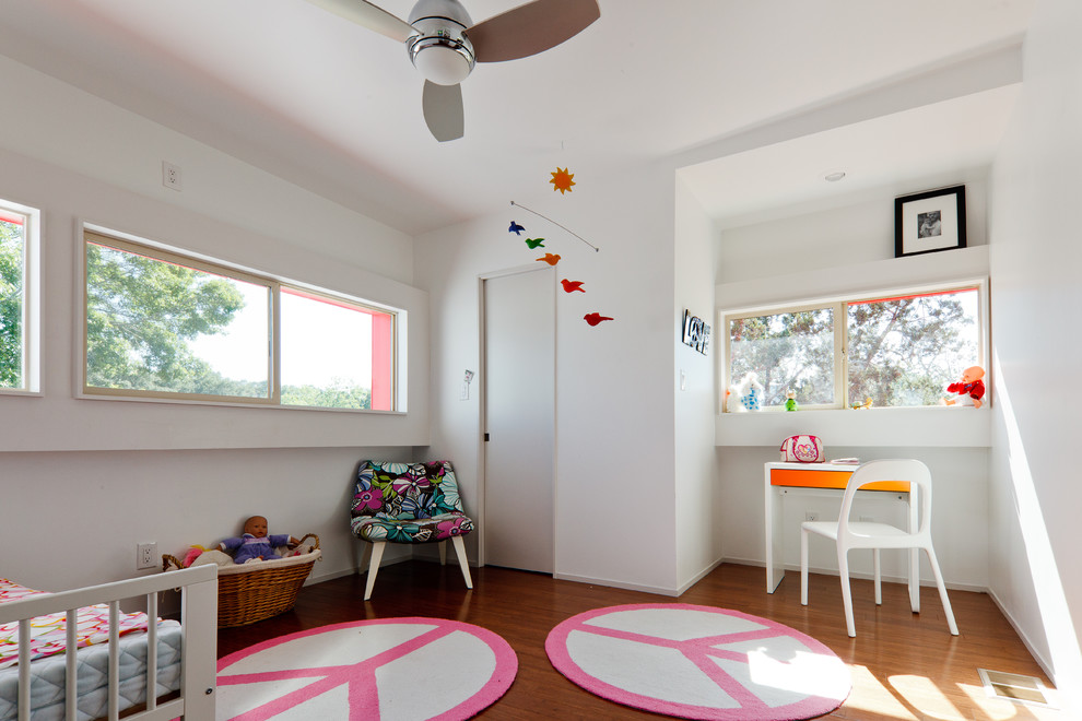 This is an example of a modern kids' bedroom for kids 4-10 years old and girls in Austin with white walls and medium hardwood floors.