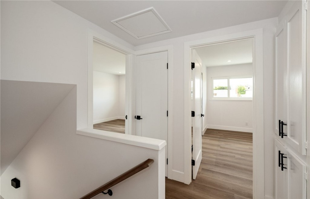 Пример оригинального дизайна: коридор в современном стиле с белыми стенами, паркетным полом среднего тона и коричневым полом