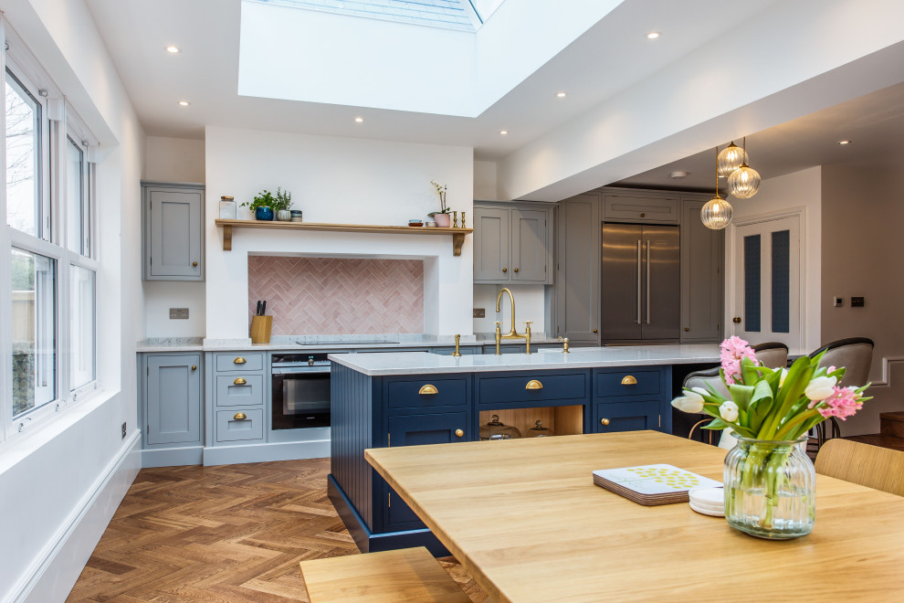 Photo of a traditional kitchen/diner in Sussex with shaker cabinets, quartz worktops, an island and a chimney breast.