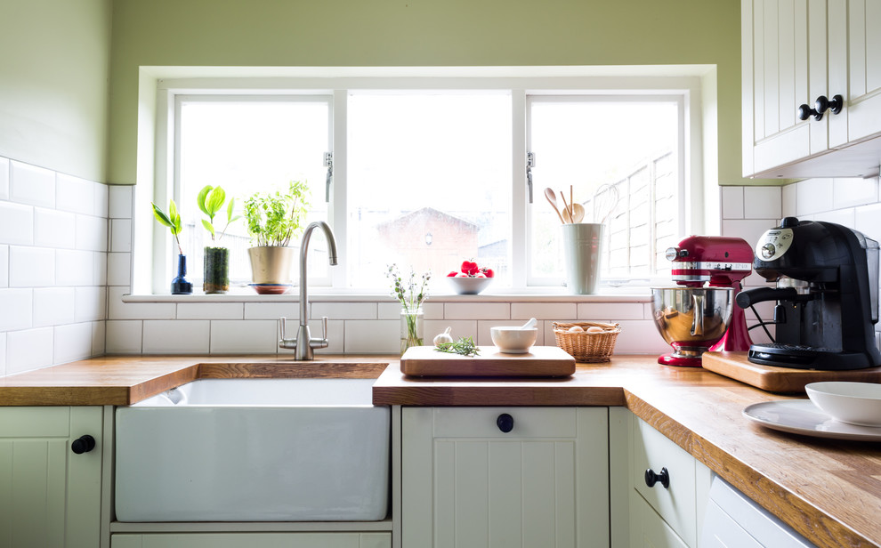 Inspiration for a small traditional grey and cream l-shaped enclosed kitchen in Essex with shaker cabinets, white cabinets, no island, a belfast sink, wood worktops, white splashback, ceramic splashback and ceramic flooring.