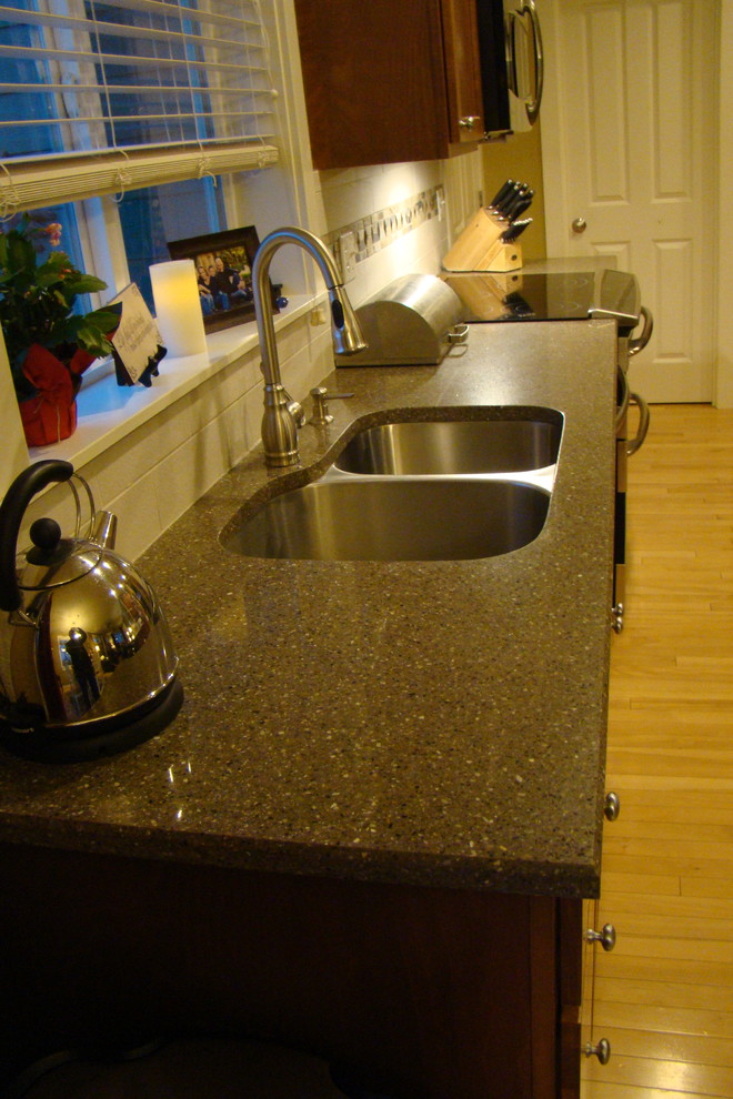 Mid-sized transitional galley light wood floor eat-in kitchen photo with an undermount sink, raised-panel cabinets, brown cabinets, quartz countertops, white backsplash, porcelain backsplash, stainless steel appliances, yellow walls and a peninsula