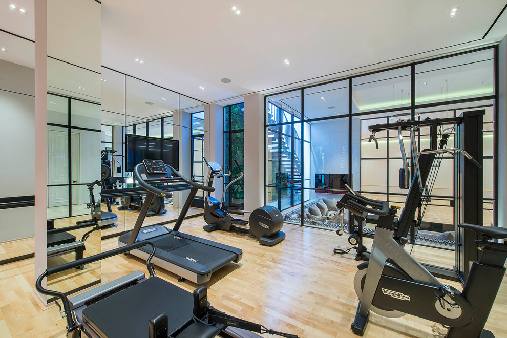 Design ideas for a large transitional home gym in London with beige floor and light hardwood floors.