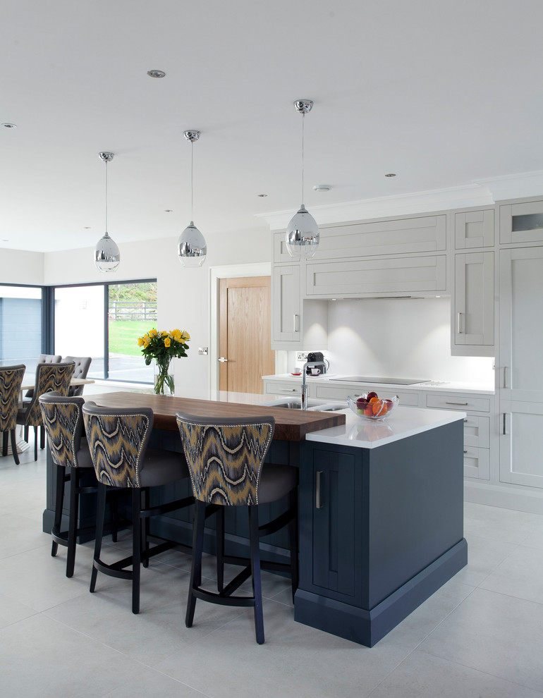 Photo of a mid-sized transitional single-wall open plan kitchen in Dublin with shaker cabinets, white cabinets, with island, a double-bowl sink, grey splashback, panelled appliances and grey floor.