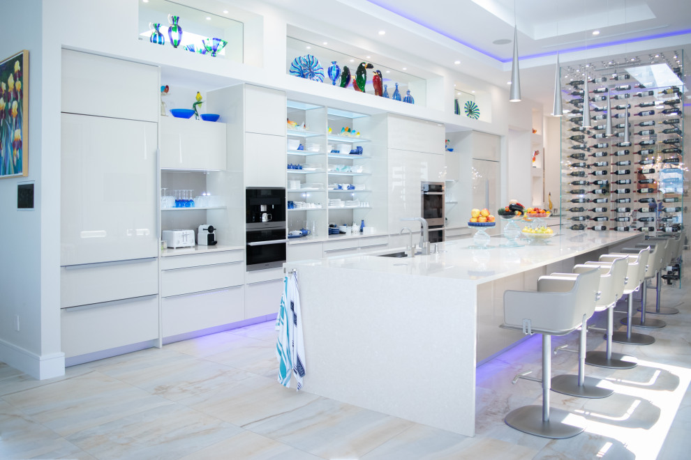 Design ideas for an expansive contemporary galley kitchen in Miami with an undermount sink, flat-panel cabinets, white cabinets, stainless steel appliances, with island, beige floor, white benchtop and recessed.