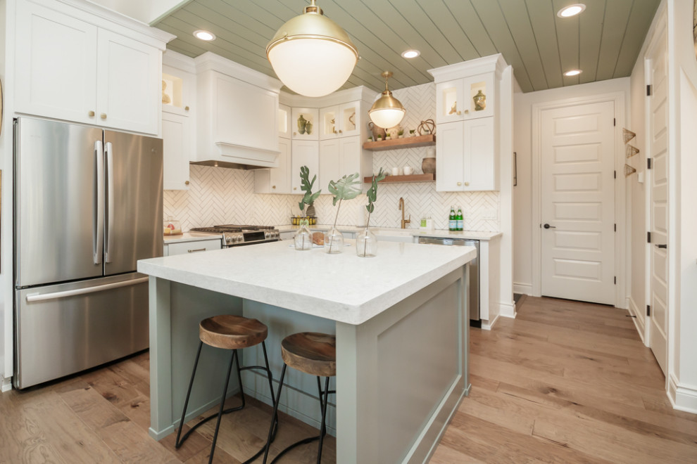 Photo of a large transitional u-shaped open plan kitchen in Atlanta with a farmhouse sink, shaker cabinets, white cabinets, quartz benchtops, white splashback, subway tile splashback, stainless steel appliances, medium hardwood floors, with island, brown floor, white benchtop and timber.