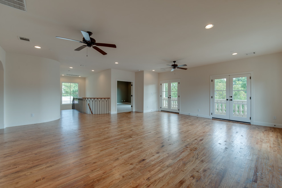 Photo of a large mediterranean open concept family room in Dallas with a game room, white walls and light hardwood floors.