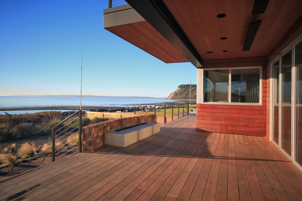 Inspiration for a mid-sized beach style backyard deck in Seattle with a fire feature and a roof extension.