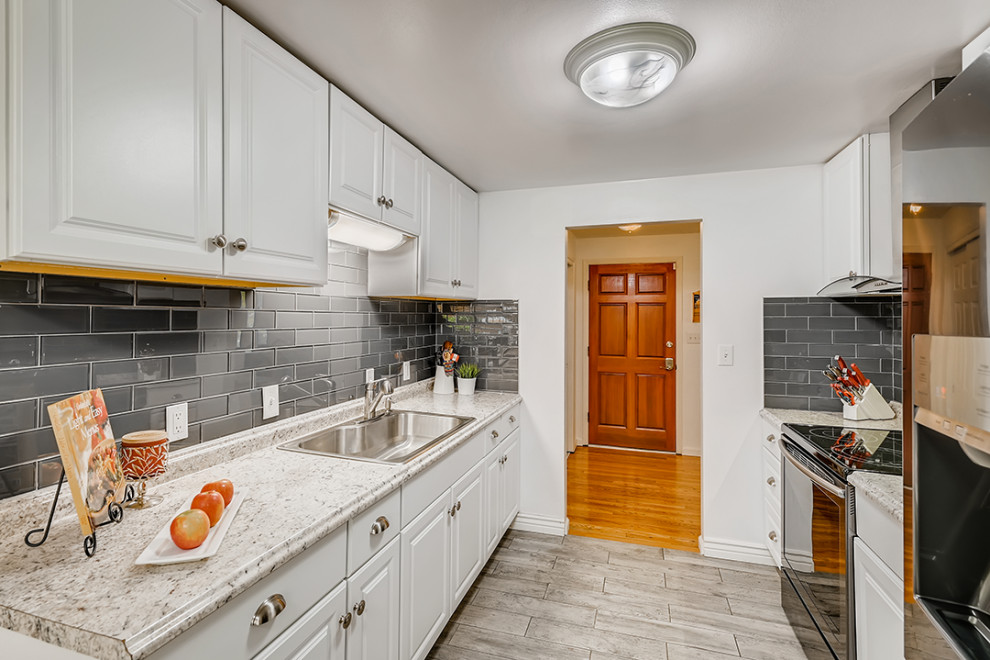 Mediterrane Wohnküche mit Küchenrückwand in Schwarz, Rückwand aus Keramikfliesen, Laminat und grauem Boden in Denver