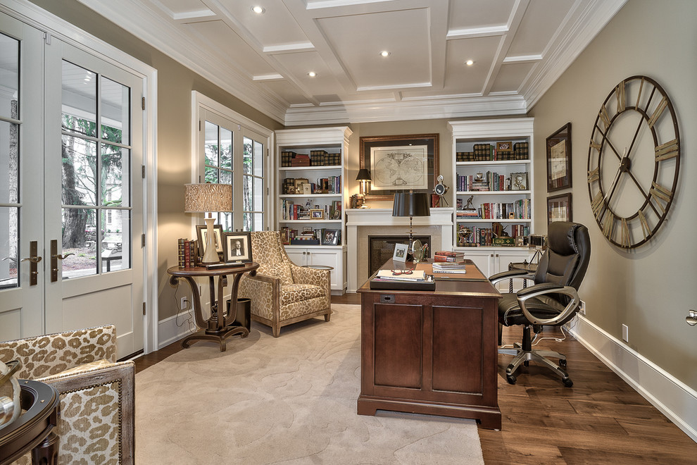 This is an example of a mid-sized transitional study room in Toronto with beige walls, dark hardwood floors, a standard fireplace, a tile fireplace surround, a freestanding desk and brown floor.