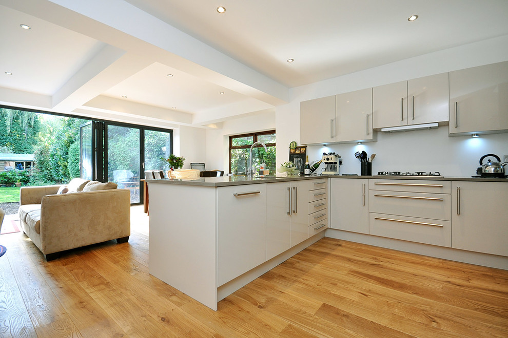 Modern kitchen/diner in London with a single-bowl sink, open cabinets, white cabinets, granite worktops, grey splashback, metal splashback, stainless steel appliances, an island and medium hardwood flooring.