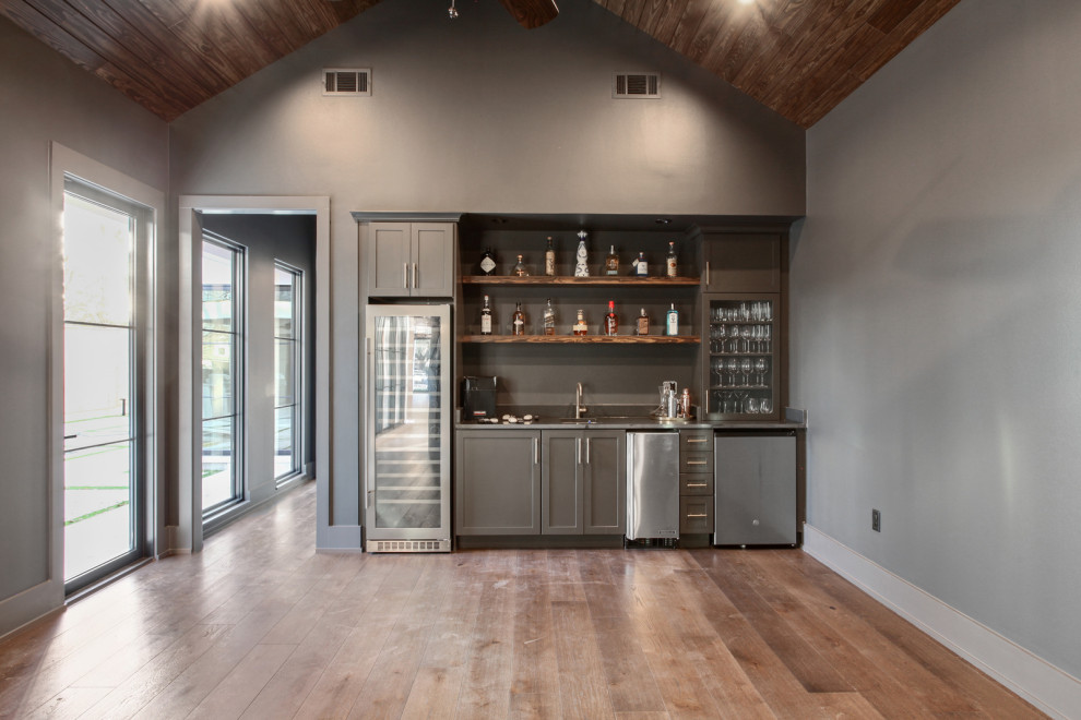 Inspiration for a mid-sized transitional single-wall wet bar in New Orleans with an undermount sink, shaker cabinets, grey cabinets, concrete benchtops, grey splashback, dark hardwood floors, brown floor and grey benchtop.