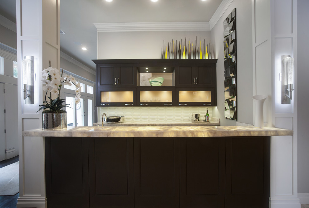 Example of a mid-sized transitional u-shaped porcelain tile and beige floor enclosed kitchen design with raised-panel cabinets, brown cabinets, beige backsplash, glass tile backsplash, stainless steel appliances and an island