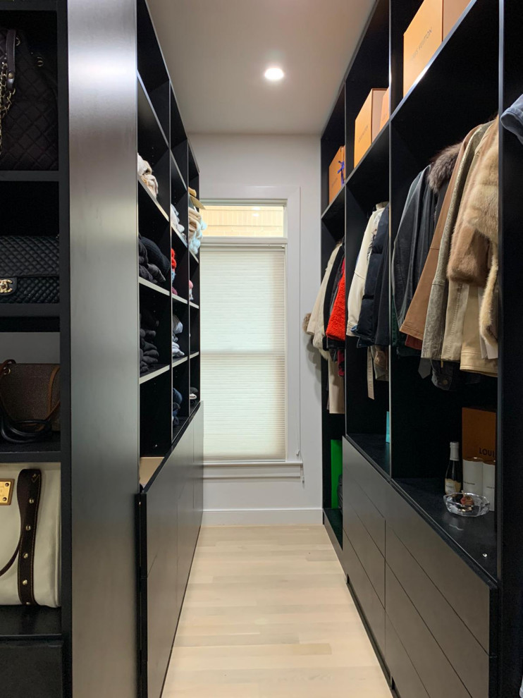 Modelo de armario vestidor de mujer moderno grande con armarios con paneles lisos, puertas de armario negras, suelo laminado y suelo beige