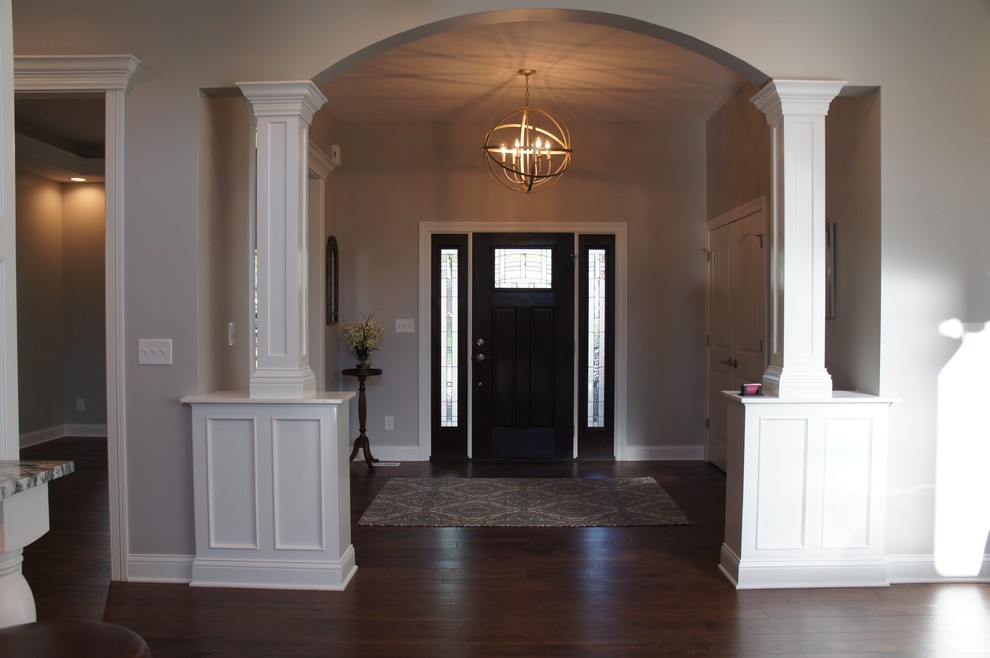 Example of a transitional dark wood floor foyer design with beige walls and a dark wood front door